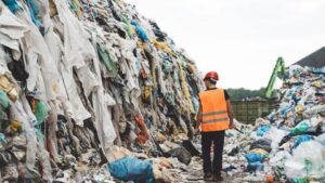 Enjeux de la fast fashion sur l'environnement avec pile de vêtements usagés et globe terrestre en arrière-plan