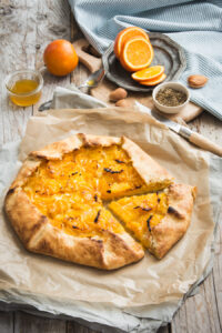 Oranges fraîches entassées avec des feuilles vertes sur fond de bois rustique