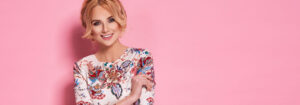 femme souriante portant des vêtements en coton bio se tenant dans un champ de blé ensoleillé pour illustrer la mode écoresponsable